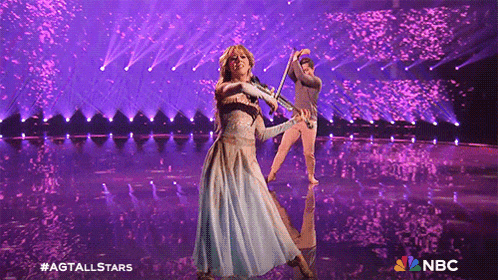 a woman in a blue dress playing a violin on a stage with nbc written on the bottom