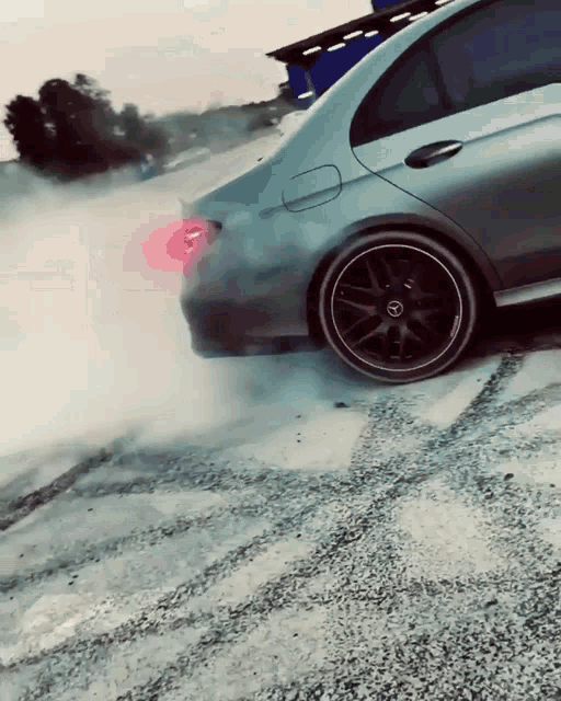 a car is driving down a gravel road and smoke is coming out of the tires