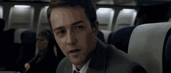 a man in a suit and tie is sitting on an airplane .