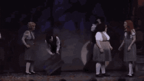 a group of young girls are holding hands on a stage .