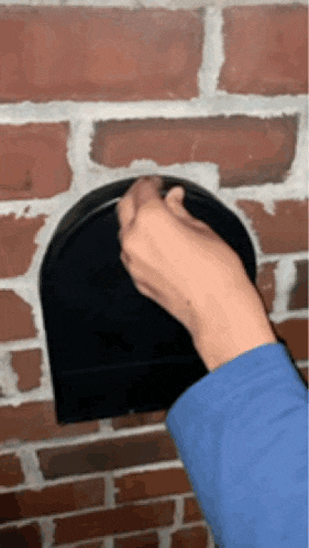 a person 's hand is reaching into a mailbox on a brick wall