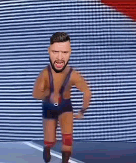 a wrestler with a beard is running on a stage without a shirt on .