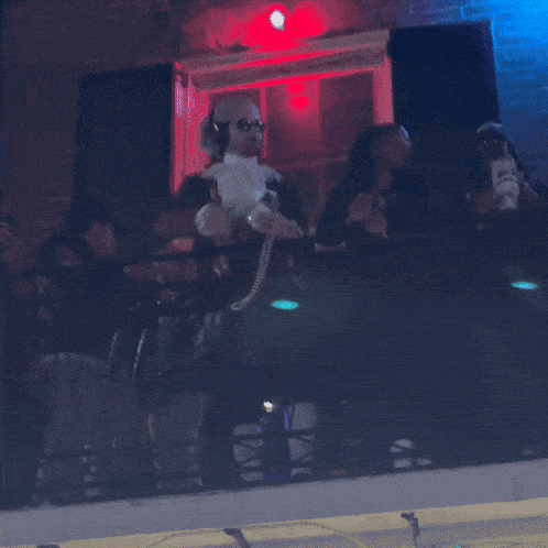 a group of people are sitting on a balcony with a purple light behind them