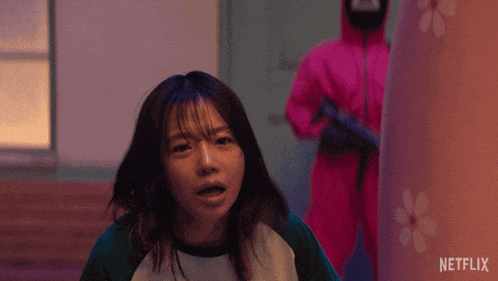 a girl in a green and white shirt is standing in front of a man in a pink suit with a netflix logo on it