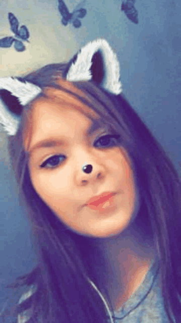a young girl wearing cat ears and headphones is taking a selfie .