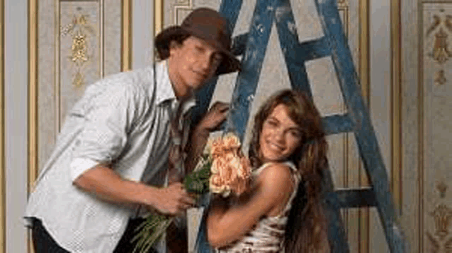 a man is giving a woman a bouquet of flowers while standing next to a blue ladder .