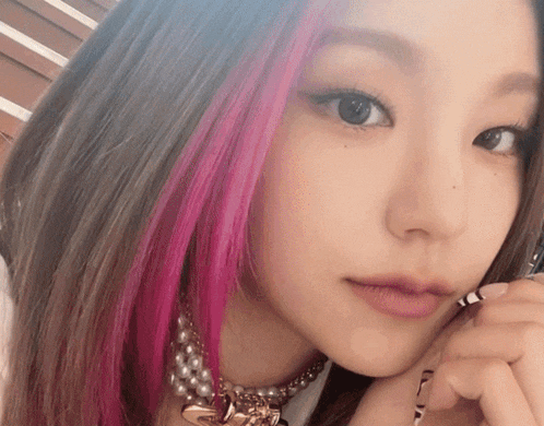 a close up of a woman with pink hair and pearls