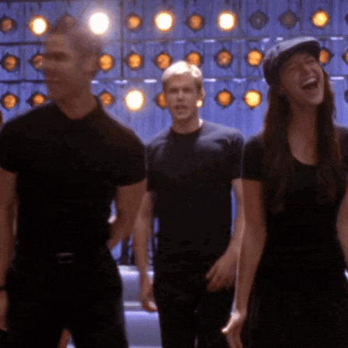 a man and a woman are standing in front of a wall of lights and laughing