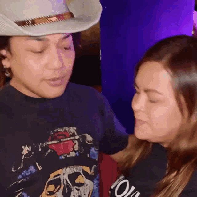 a man wearing a cowboy hat and a woman wearing a shirt that says ' i love you ' on it