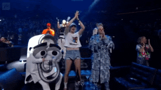 a group of people are standing on a stage with their hands in the air .