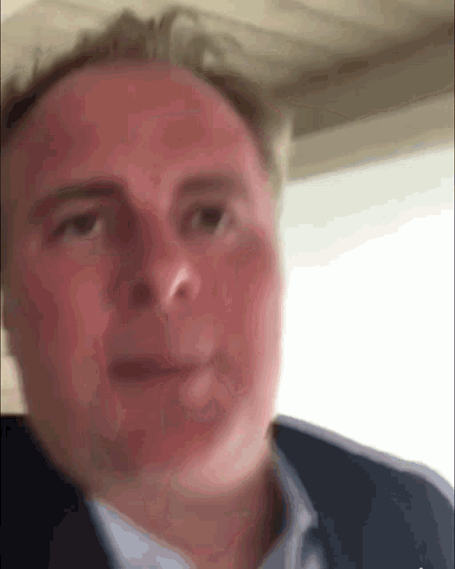 a close up of a man 's face with a blue jacket on