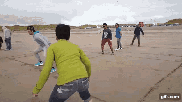 a group of people are playing a game of volleyball on a sandy beach .