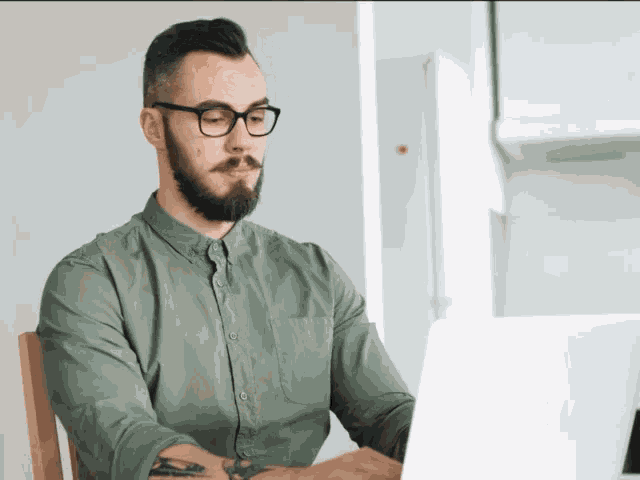 a man with glasses and a beard is using a laptop
