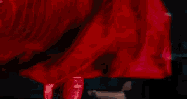 a man with his arms crossed is standing in front of a red statue .