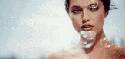 a close up of a woman blowing soap bubbles .