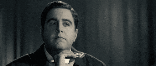 a man in a suit and tie is yawning and covering his mouth with his hand