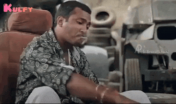 a man is sitting in a car seat smoking a cigarette