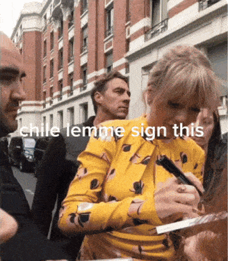 a woman in a yellow dress is signing a piece of paper with the words chile lemme sign this below her