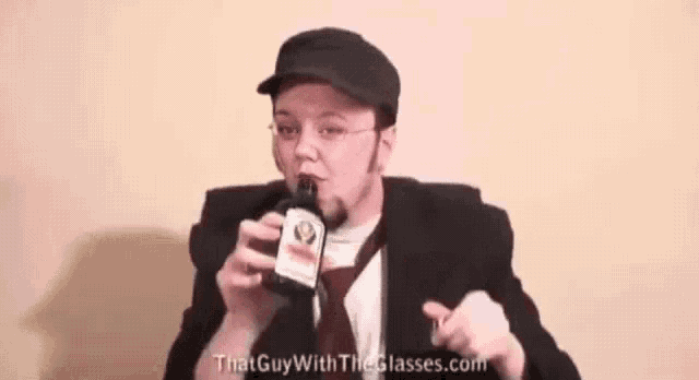 a man in a suit and tie drinking from a bottle