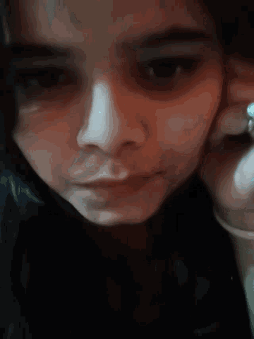a close up of a person 's face with a ring on their finger