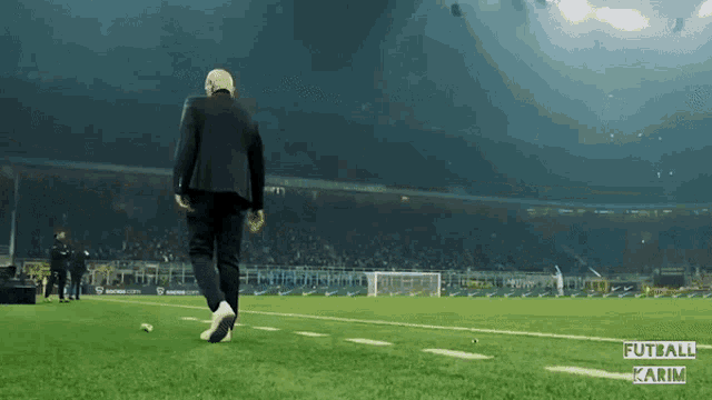 a man walking on a soccer field with the words futball karim on the bottom left