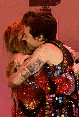 harry styles and selena gomez are hugging each other on stage .