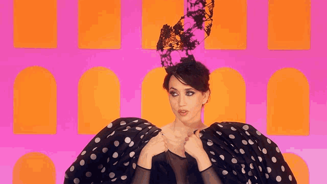 a woman wearing a black and white polka dot dress and a black hat
