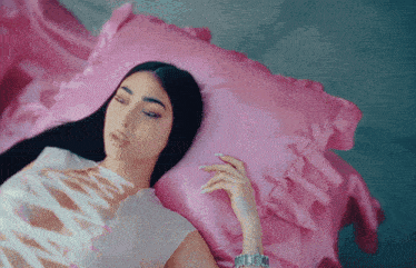 a woman wearing a watch is laying on a pink blanket