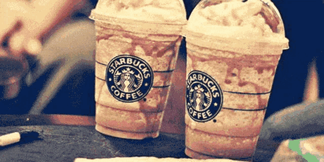 two cups of starbucks coffee sitting on a table