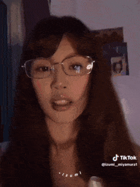 a woman wearing glasses and a necklace is making a funny face