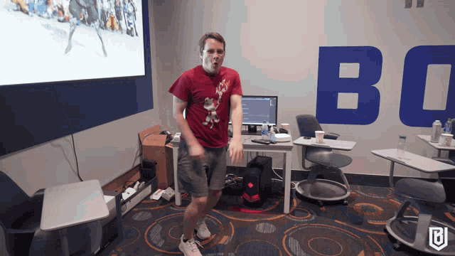 a man in a red shirt is dancing in front of a wall that says bo on it