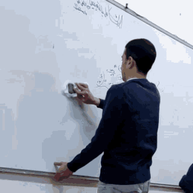 a man is cleaning a white board with arabic writing on it