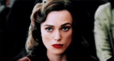 a woman with red lipstick on her lips is looking at the camera .