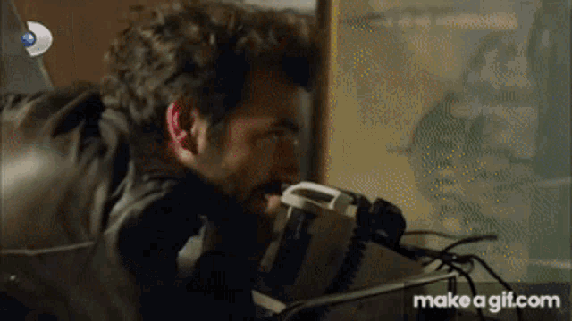 a man is looking through a microscope with make a gif.com written on the bottom