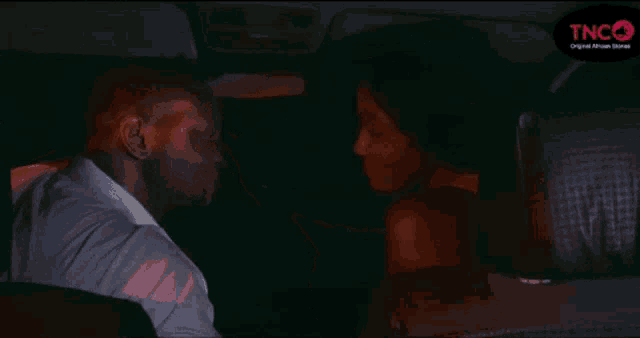 a man and woman are kissing in the back seat of a car