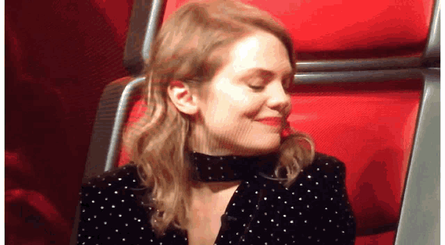 a woman in a black and white polka dot jacket is smiling