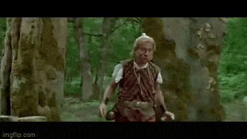 a man is standing in the middle of a forest holding a sword .
