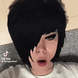 a person with black hair and a nose ring is making a funny face