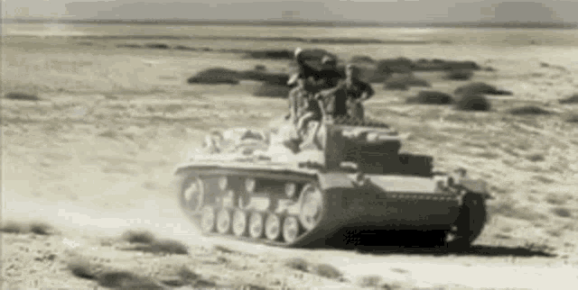 a black and white photo of a military tank driving through the desert