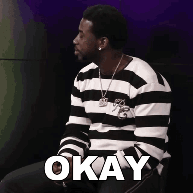 a man wearing a black and white striped shirt with the word okay in white letters