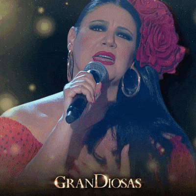 a woman singing into a microphone that says grandiosas on it