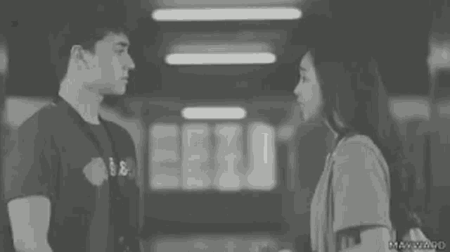 a man and a woman are standing next to each other in a black and white photo .