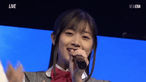 a young woman is singing into a microphone while wearing a bow tie .