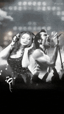 a man singing into a microphone with a woman listening to music