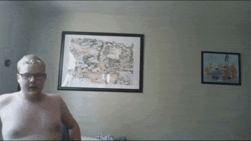 a man without a shirt is standing in front of a framed map of the united states