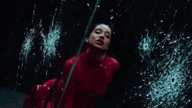a woman in a red dress is standing in front of a broken glass
