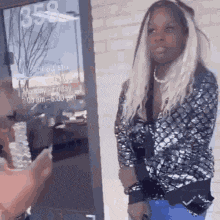 a woman with long blonde hair is standing in front of a store door .