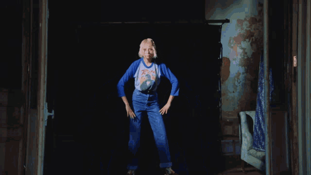 a woman standing in a dark room wearing a t-shirt that says guns n roses