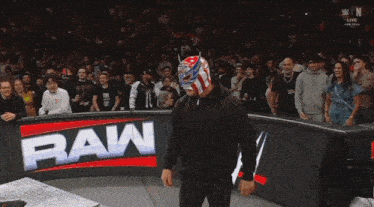 a man in a mask walks in front of a raw logo