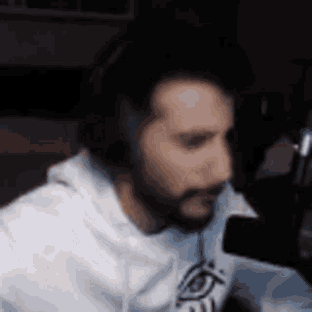 a man with a beard is sitting in front of a microphone in a dark room .